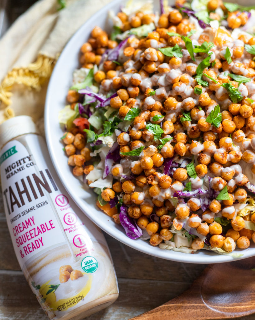 Salad topped with crispy chickpeas, chopped vegetables, and drizzled with creamy lemon tahini dressing.