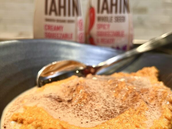 Creamy mashed sweet potatoes topped with a swirl of tahini, sprinkled with cinnamon.