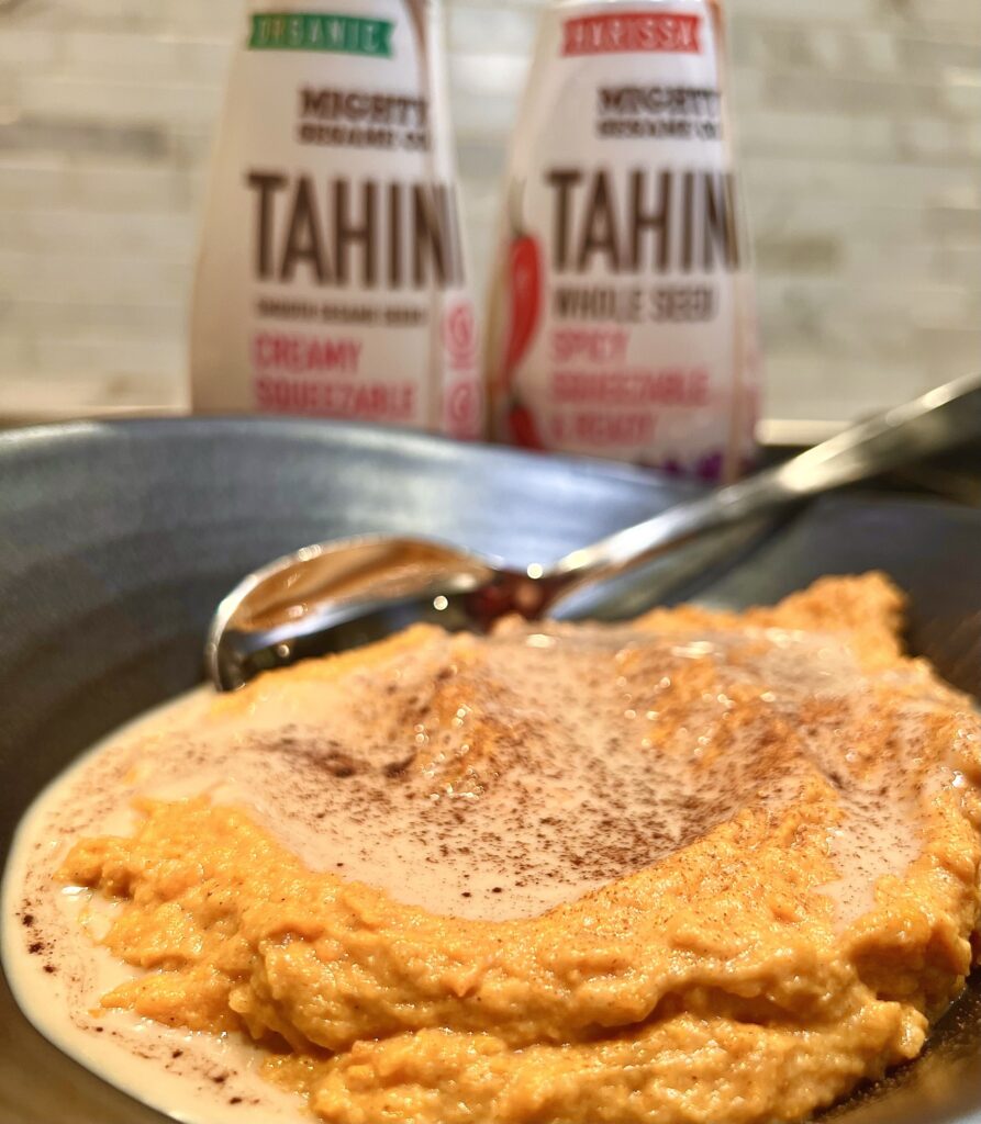 Creamy mashed sweet potatoes topped with a swirl of tahini, sprinkled with cinnamon.
