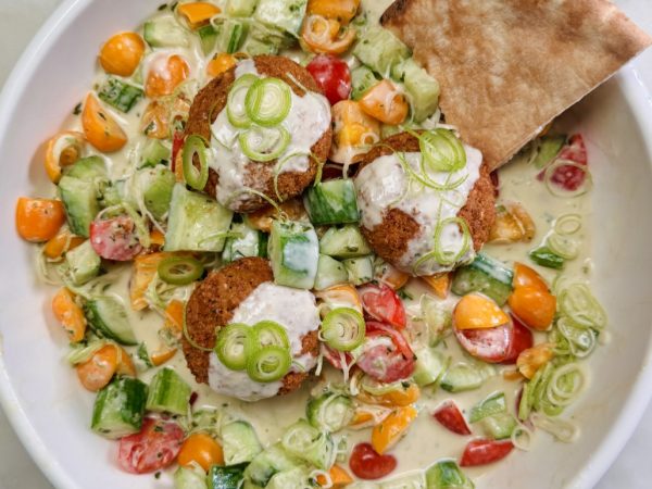 Fresh tahini salad with chopped cucumbers, tomatoes, and bell peppers, topped with dollops of creamy tahini.