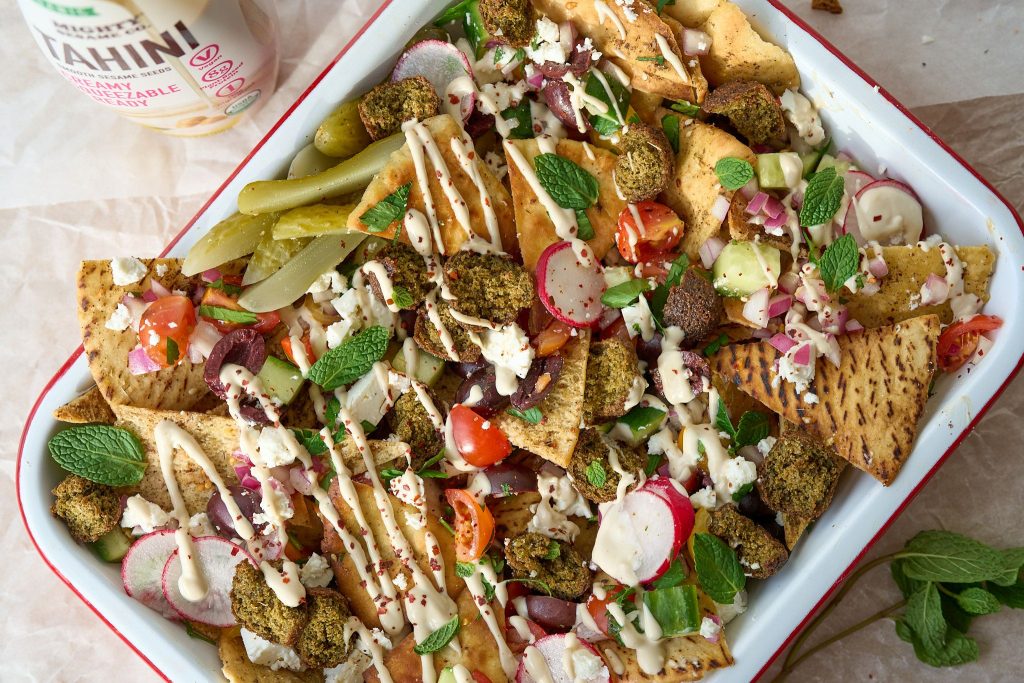 Loaded pita chips with falafel, vegetables, feta, herbs, and a creamy tahini drizzle.