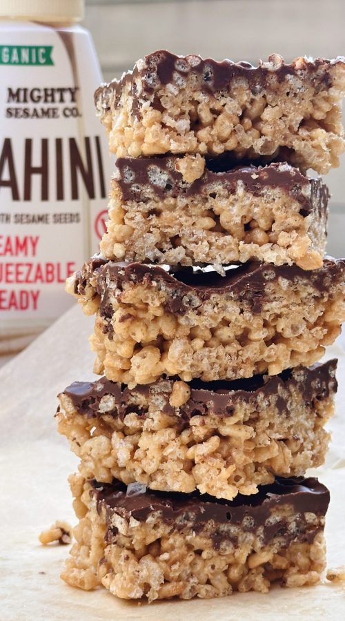 Stack of crispy treats made with tahini, topped with a layer of chocolate, highlighting a sweet and nutty flavor combination.