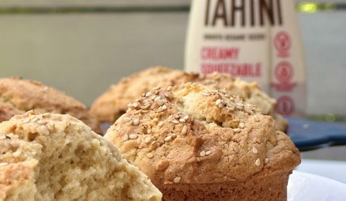 Tahini Muffins: Close-up of baked muffins with sesame seeds and a bottle of tahini in the background.