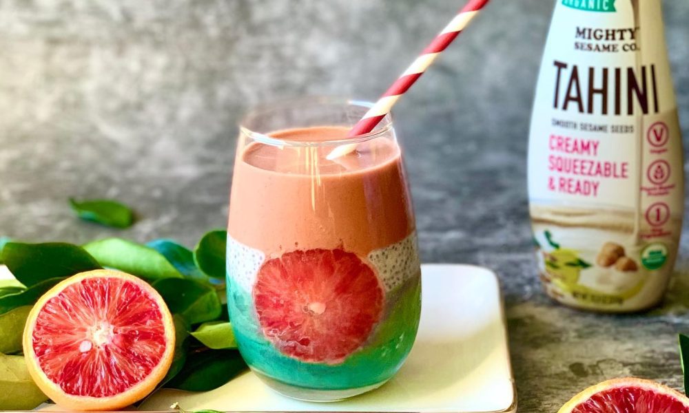 Smoothie artfully layered with Harissa Tahini and blood orange near product bottle.