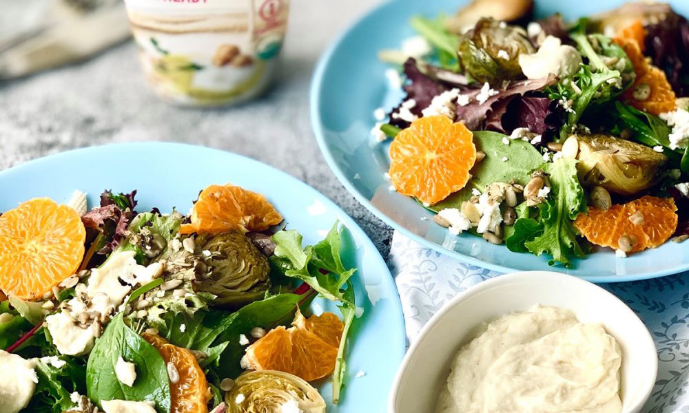 Two tahini salad plates with orange slices, artichokes and creamy dressing.